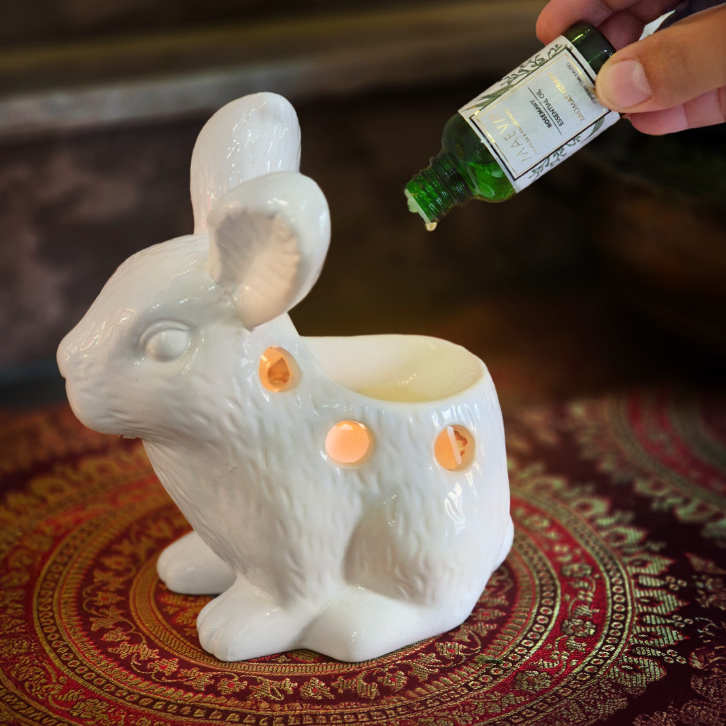 White rabbit-shaped container with a hand pouring a green liquid into it on a patterned surface.